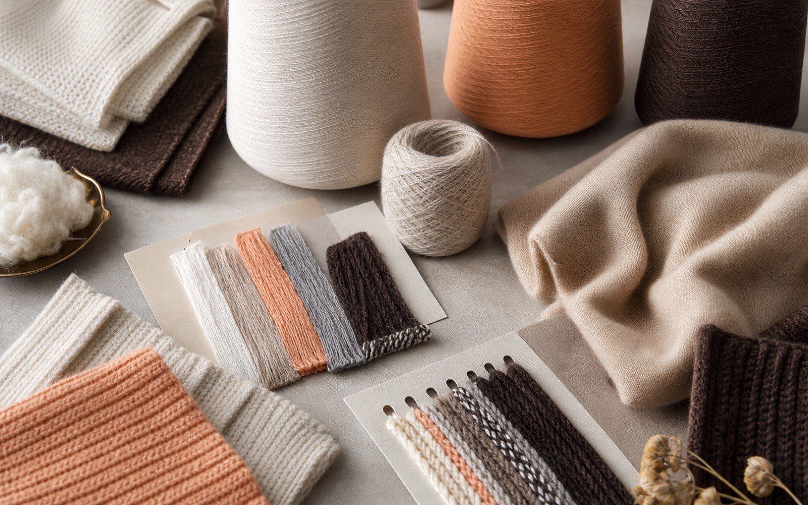 Premium yarn cones, knitted swatches and fiber sample cards arranged for blend selection